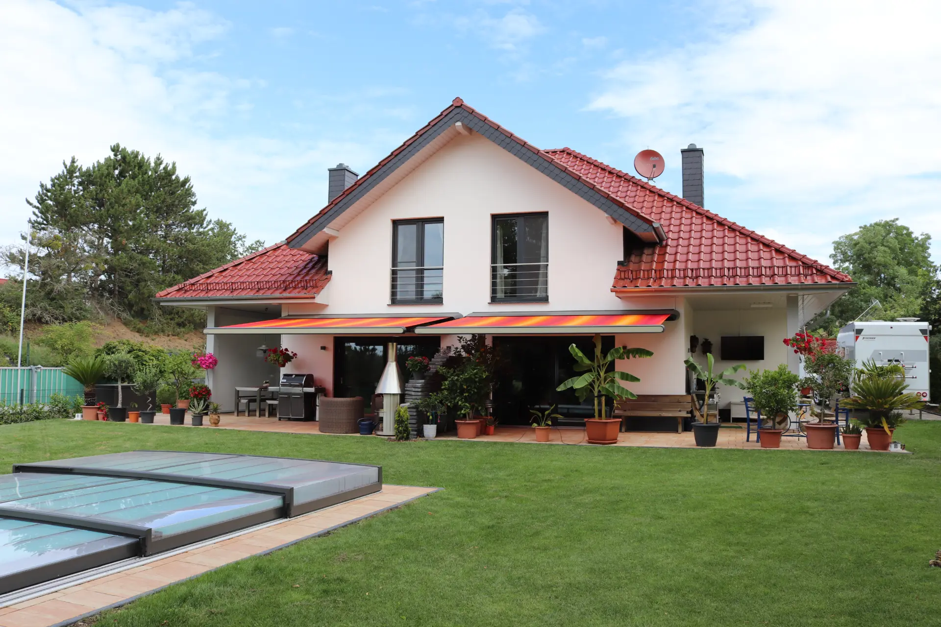 Ausgefahrene Markise über einer Terrasse mit Loungemöbeln, im Vordergrund ein Pool