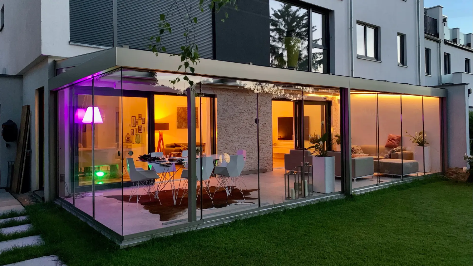 Wintergarten am Abend mit farbiger Innenbeleuchtung und Loungebereich