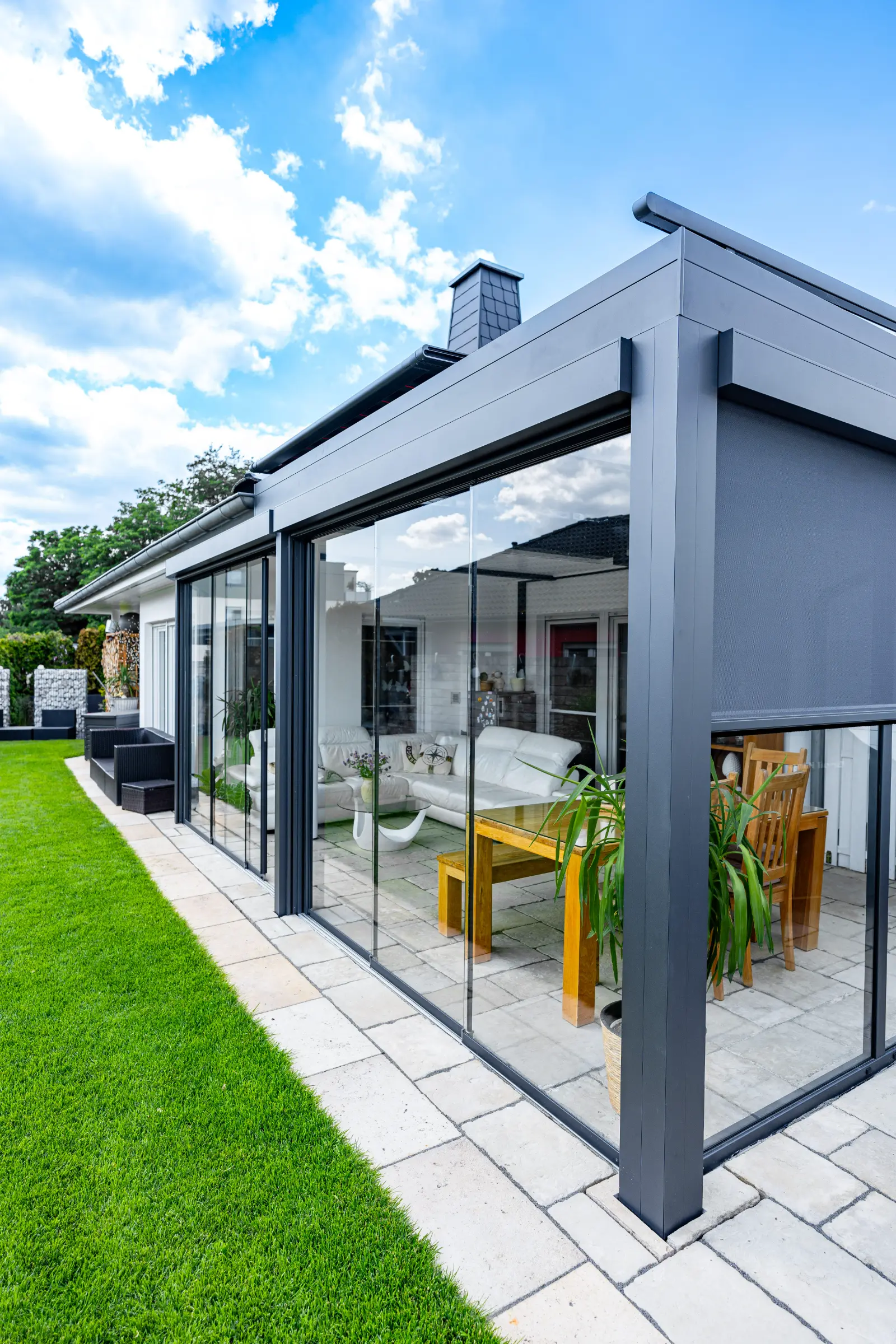 Terrassendach mit Glasschiebewänden und weißem Ledersofa im Innenraum